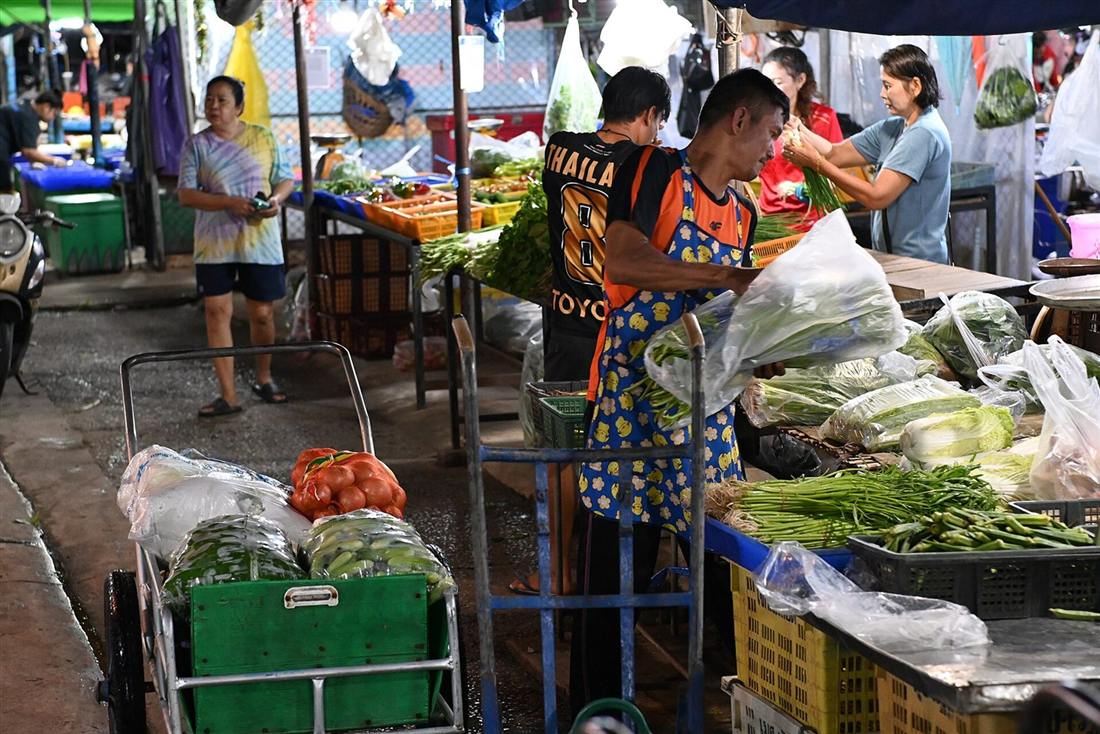 Feirante organizando frutas e verduras frescas na banca